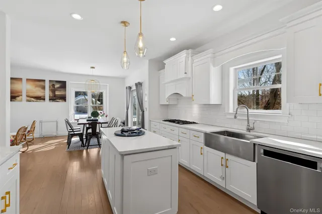 a kitchen with stainless steel appliances granite countertop a stove top oven a sink a dining table and chairs with wooden floor