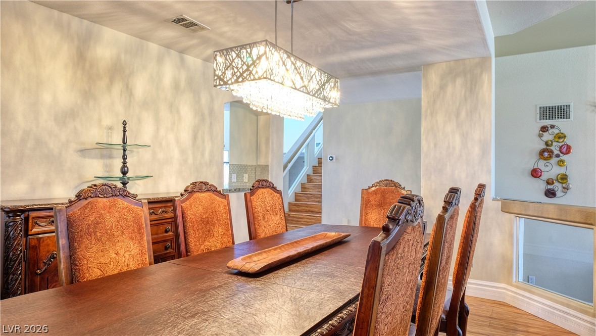 3704 North Campbell Road Las Vegas, NV 89129 - Photo 10 of 38 A striking linear chandelier illuminates a formal dining area, complementing the rich wood tones and textured walls.