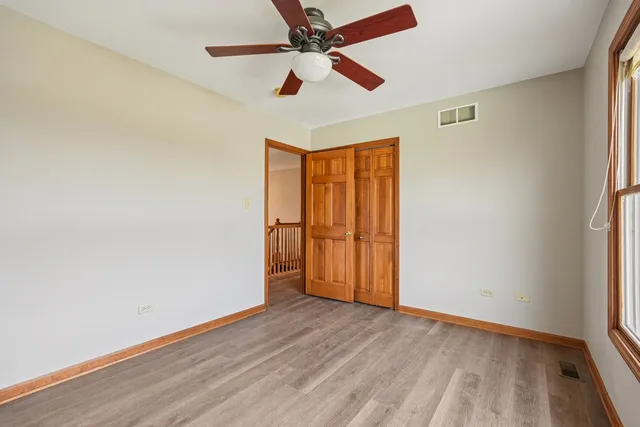 an empty room with wooden floor fan and windows