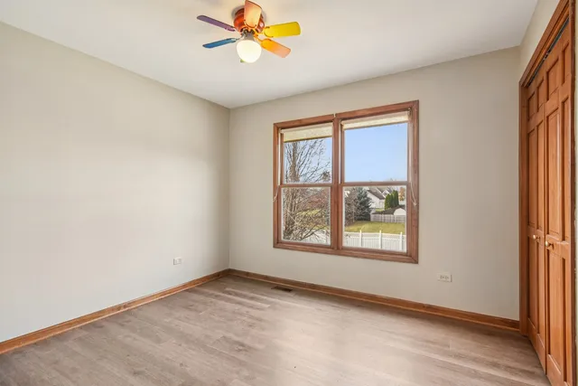 an empty room with windows and fan