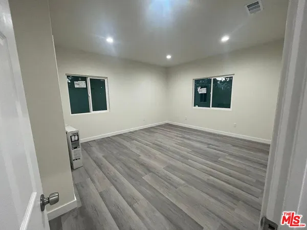 an empty room with wooden floor and windows