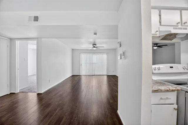 a view of a hallway with wooden floor and cabinet
