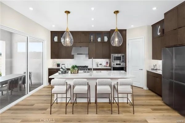 a kitchen with stainless steel appliances kitchen island granite countertop a dining table chairs and a refrigerator