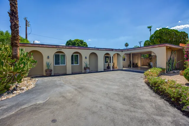 a view of a white house with a big yard and potted plants