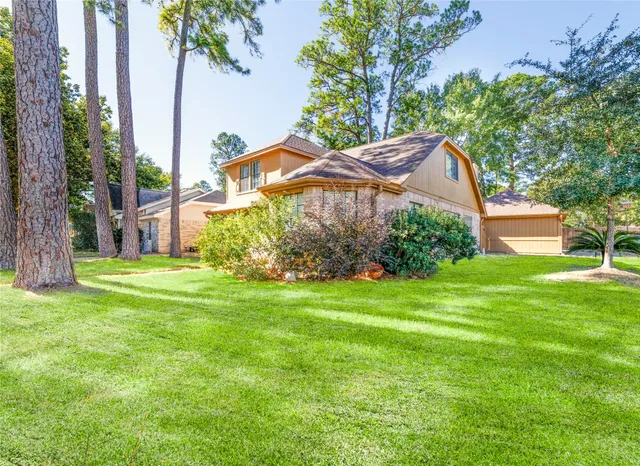 a view of a house next to a big yard and large trees