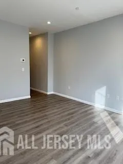 a view of an empty room with wooden floor and closet