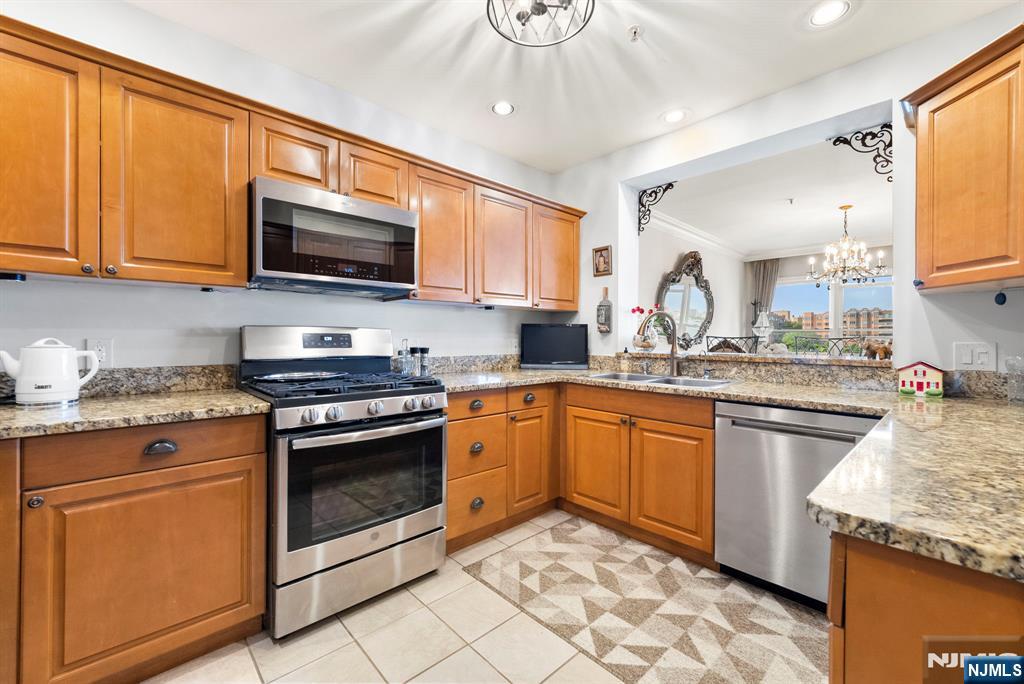 108 The Promenade, Unit 108 Edgewater, NJ 07020 - Photo 10 of 49 a kitchen with stainless steel appliances granite countertop a stove sink microwave and cabinets