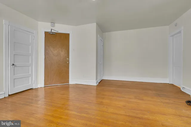 a view of an empty room with wooden floor and closet