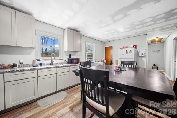 a kitchen with stainless steel appliances granite countertop a stove a sink dishwasher a dining table and chairs with wooden floor