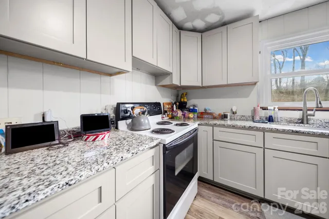 a kitchen with kitchen island granite countertop a sink a stove and cabinets