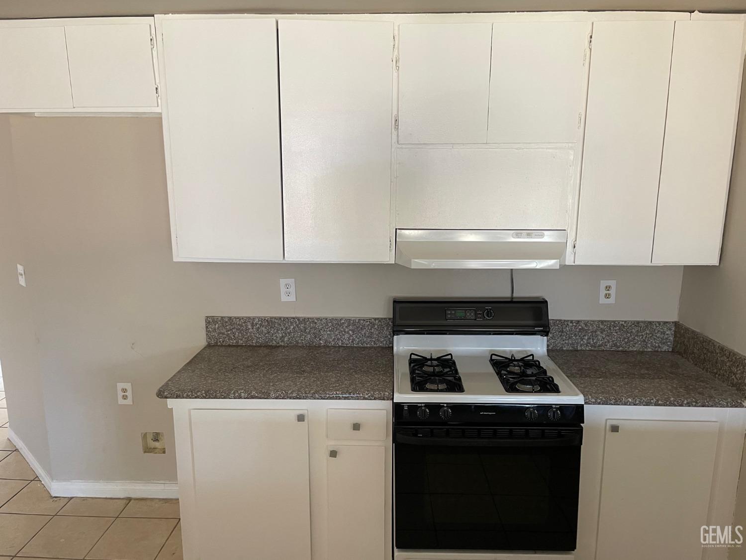 Undisclosed Address Bakersfield, CA 93307 - Photo 7 of 20 a kitchen with granite countertop white cabinets and white stove