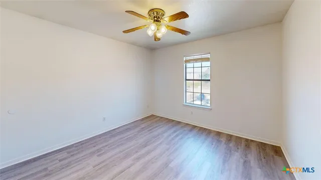 an empty room with a window and a chandelier fan