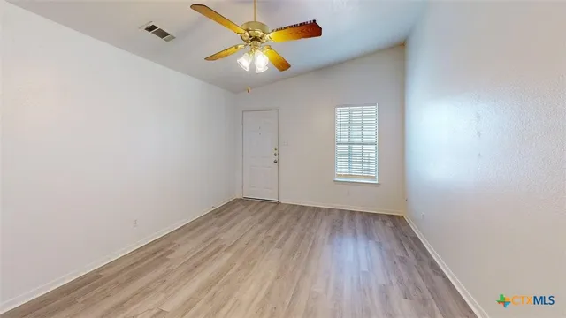 an empty room with wooden floor and windows