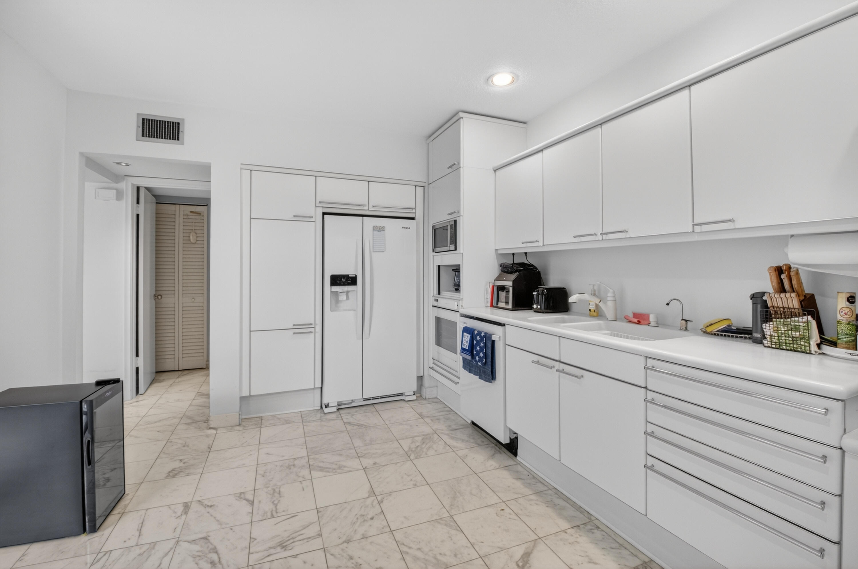 7369 Orangewood Lane, Unit 307 Boca Raton, FL 33433 - Photo 12 of 37 a kitchen with granite countertop a refrigerator and white cabinets