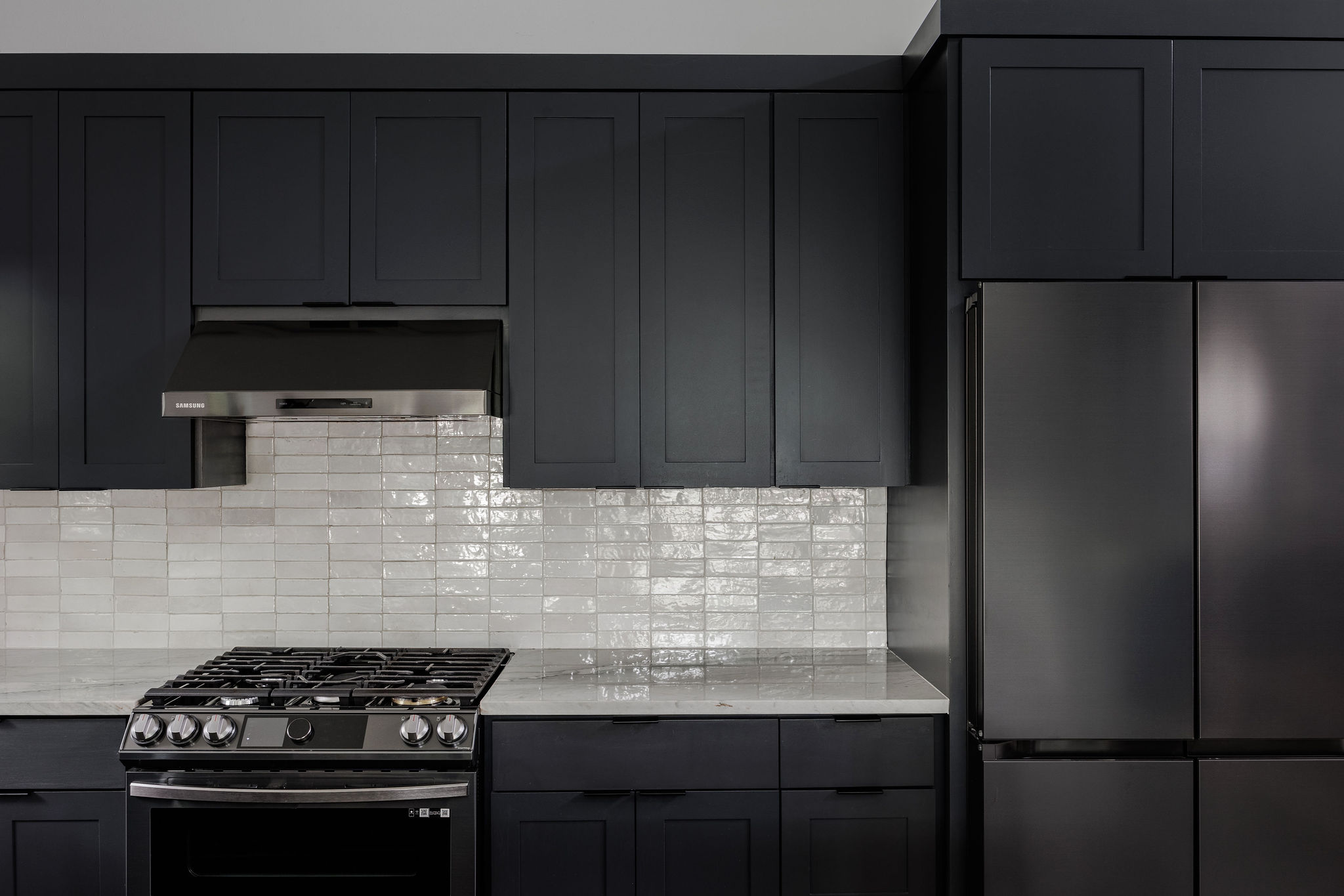 1605 Maple Avenue Austin, TX 78702 - Photo 11 of 33 Contemporary kitchen featuring dark cabinetry, a gas range with a stainless steel range hood, light-toned tiled backsplash, and a dark-finish refrigerator