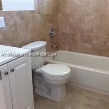 a bathroom with a granite countertop toilet and a bathtub