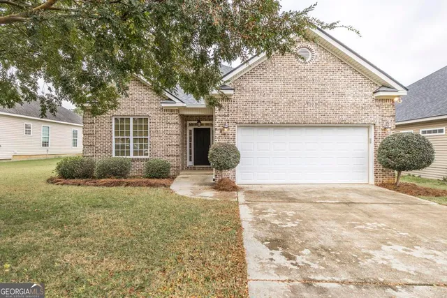 a view of a house with backyard and trees