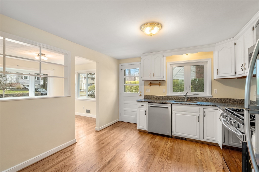 125 Lyman Road Milton, MA 02186 - Photo 13 of 25 a kitchen with stainless steel appliances granite countertop a stove a sink and white cabinets with wooden floor next to windows