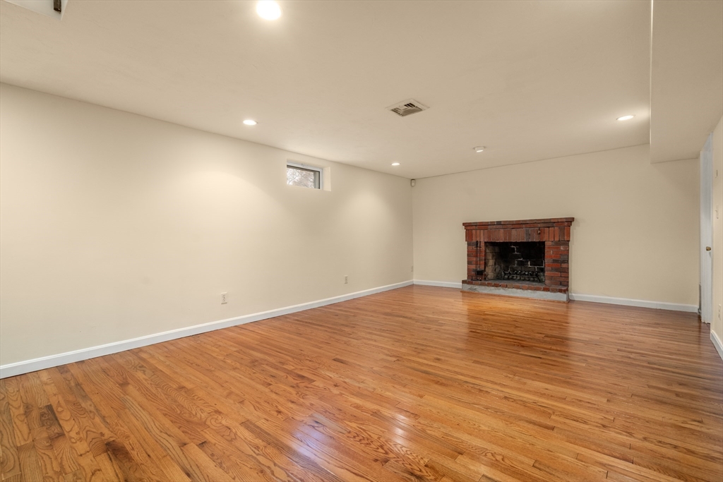 125 Lyman Road Milton, MA 02186 - Photo 19 of 25 an empty room with wooden floor and a fireplace