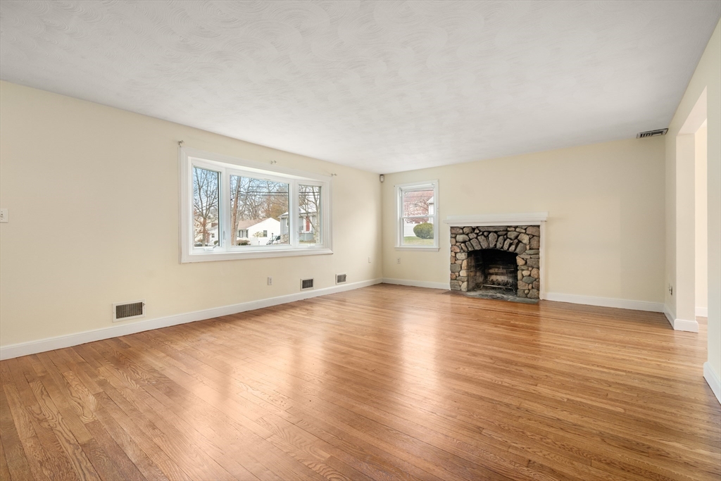 125 Lyman Road Milton, MA 02186 - Photo 6 of 25 a view of empty room with wooden floor and fireplace