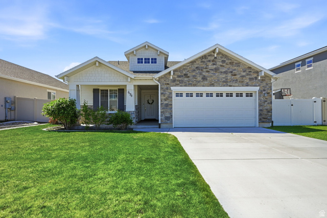 1175 Silver Hollow Road Syracuse, UT 84075 - Photo 2 of 34 Stone facade and shake siding exterior featuring a covered entry, an attached two-car garage, an extended concrete driveway, and a manicured lawn