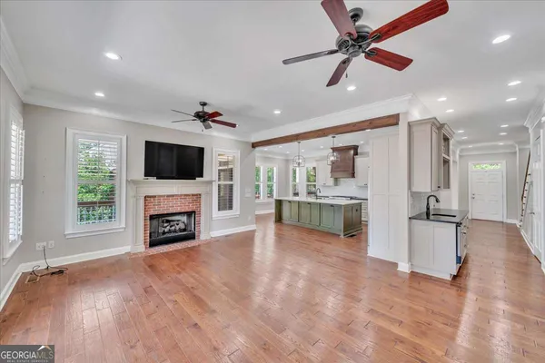 a view of a livingroom with a fireplace a ceiling fan and wooden floor