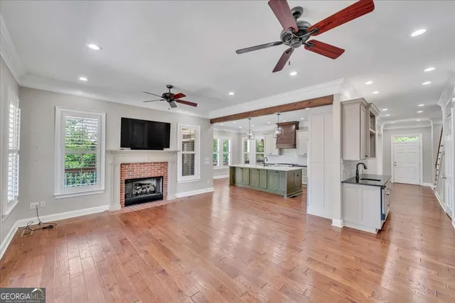 a view of a livingroom with a fireplace a ceiling fan and wooden floor
