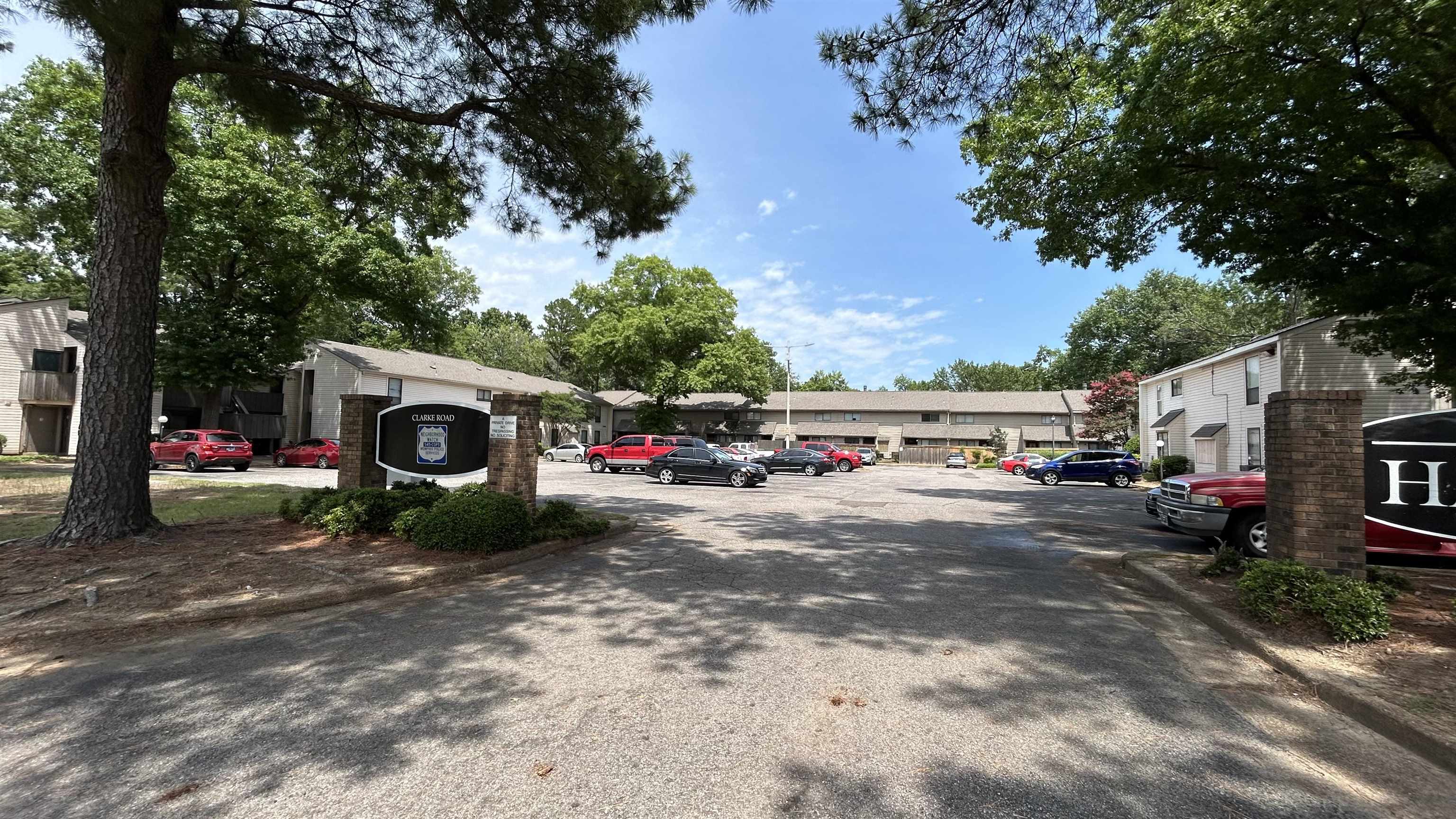 2800 Clarke Road, Unit 2 Memphis, TN 38115 - Photo 3 of 18 Paved parking area surrounded by mature trees, featuring brick-columned signage and multi-story residential buildings