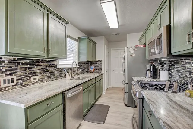 a kitchen with stainless steel appliances granite countertop a stove a sink and a refrigerator