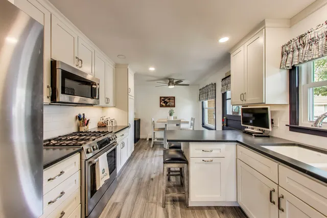 a kitchen with cabinets a sink a stove a oven a dining table and chairs