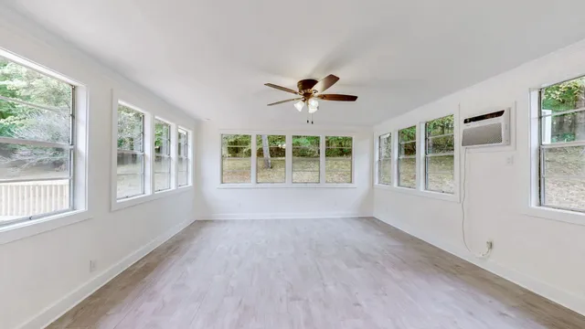 a view of an empty room with a window and wooden floor