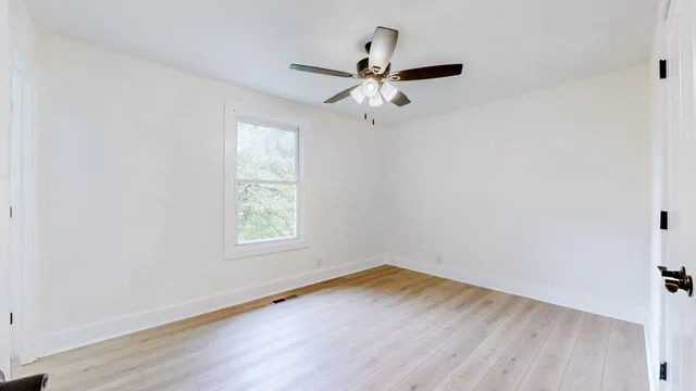 a view of a livingroom with a chandelier fan and wooden floor