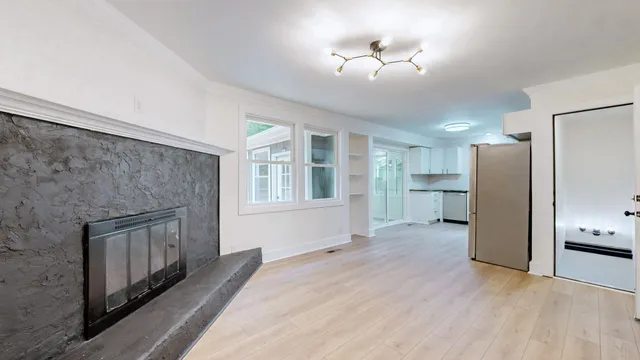 a view of an empty room with a window and a kitchen