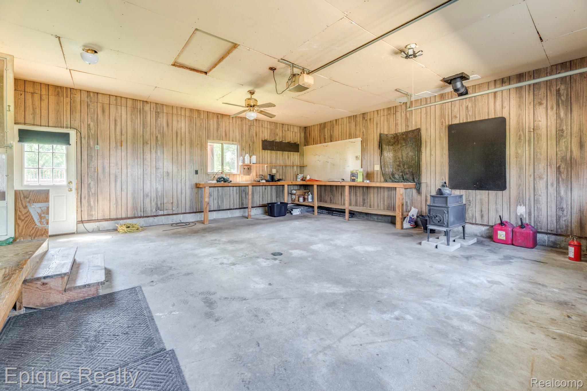 11110 Davison Road Davison, MI 48423 - Photo 50 of 65 Garage with a ceiling fan, wood walls, and a garage door opener