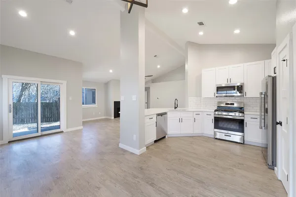 a large kitchen with stainless steel appliances kitchen island granite countertop a stove top oven a sink and a refrigerator