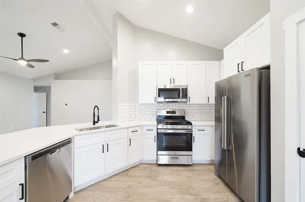 a kitchen with a sink stainless steel appliances and white cabinets