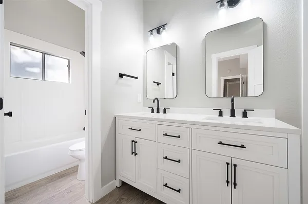 a bathroom with a double vanity sink mirror and bathtub