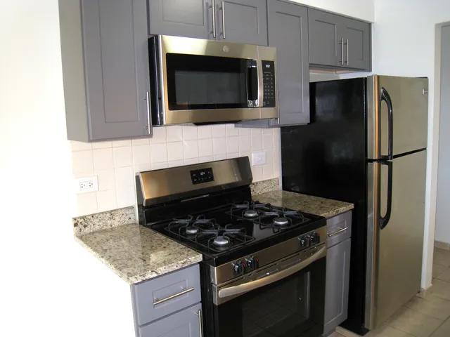 a kitchen with stainless steel appliances granite countertop a stove microwave and refrigerator
