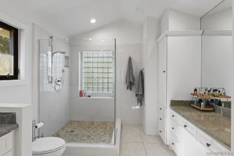 a bathroom with a granite countertop sink a mirror a toilet and shower