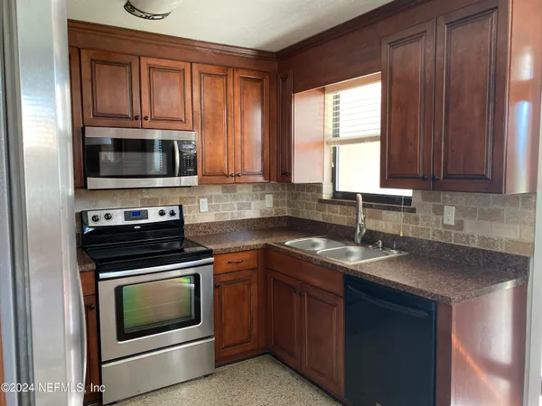 a kitchen with granite countertop a stove top oven microwave and sink