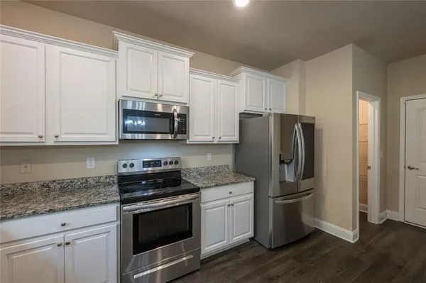 a kitchen with granite countertop white cabinets and stainless steel appliances