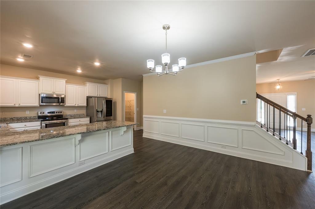 12172 Flannery Lane Hampton, GA 30228 - Photo 8 of 31 a kitchen with stainless steel appliances a microwave a stove a sink dishwasher a refrigerator and white cabinets with wooden floor