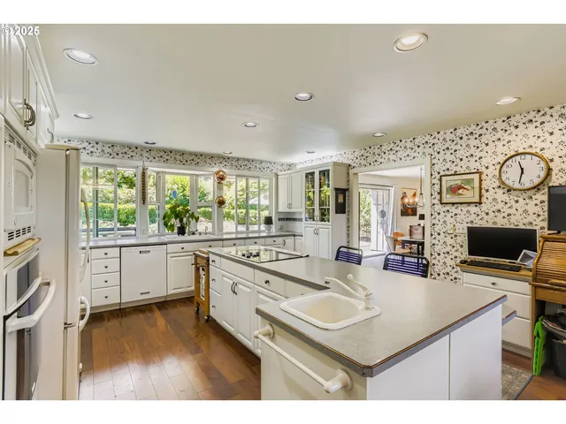 a kitchen with kitchen island a stove a sink a oven a dining table and chairs with wooden floor