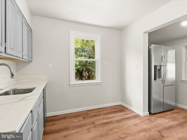a view of a kitchen that shows a sink and dishwasher with wooden floor