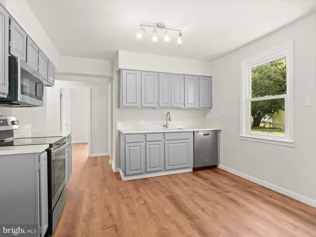 a kitchen with stainless steel appliances granite countertop a stove a sink dishwasher and a refrigerator with wooden floor