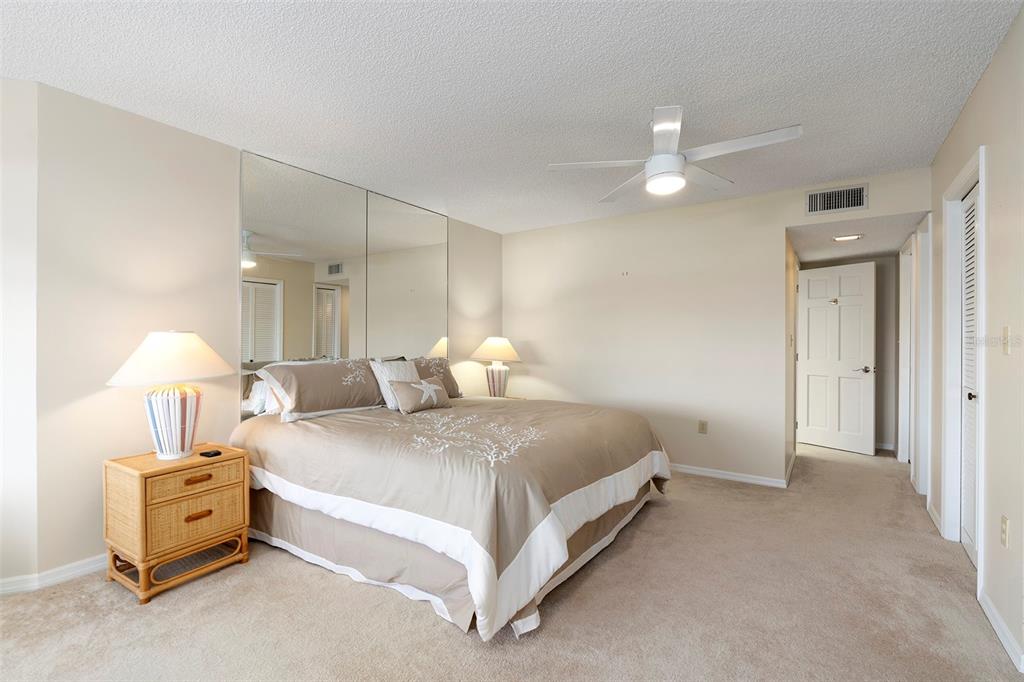 6500 Sunset Way, Unit 116 St. Pete Beach, FL 33706 - Photo 16 of 56 a spacious bedroom with a bed and a lamp