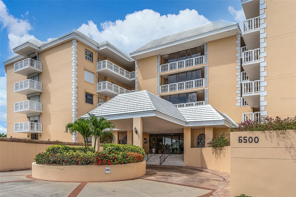 6500 Sunset Way, Unit 116 St. Pete Beach, FL 33706 - Photo 41 of 56 a front view of a residential apartment building with a yard and potted plants