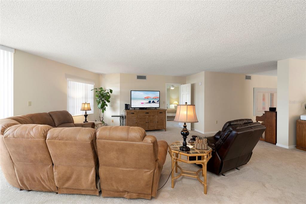 6500 Sunset Way, Unit 116 St. Pete Beach, FL 33706 - Photo 5 of 56 a living room with furniture a flat screen tv and a window