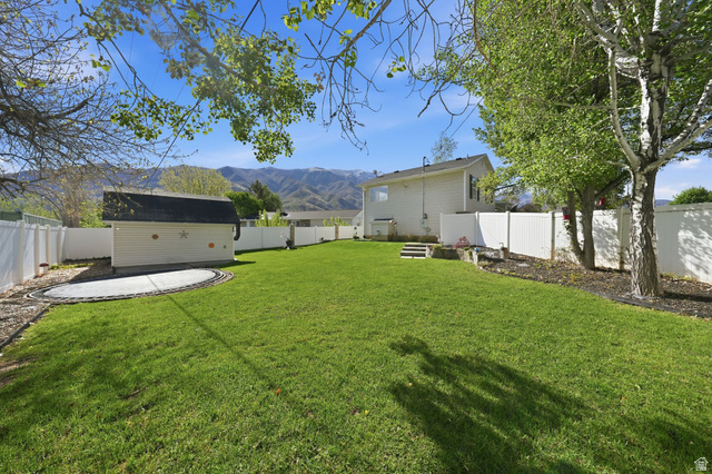 415 East 400 North Santaquin, UT 84655 - Photo 31 of 39 Expansive backyard featuring a manicured lawn, white privacy fencing, and a dedicated trampoline area