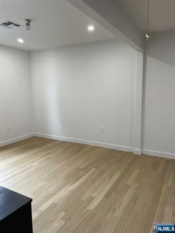 an empty room with wooden floor and fan